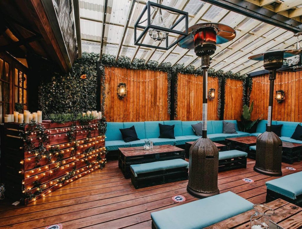 a venue room with fairy lights, wooden walls, and blue seats